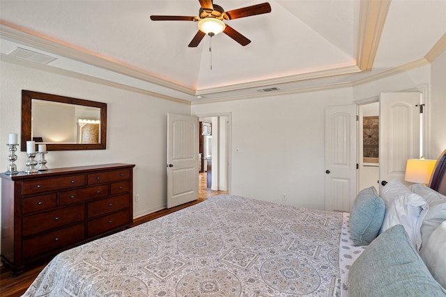 bedroom featuring visible vents, a raised ceiling, dark wood-style flooring, and crown molding