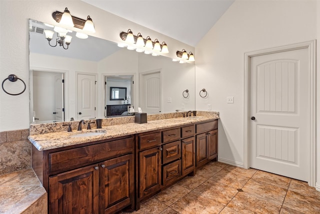 bathroom featuring vaulted ceiling, double vanity, and a sink