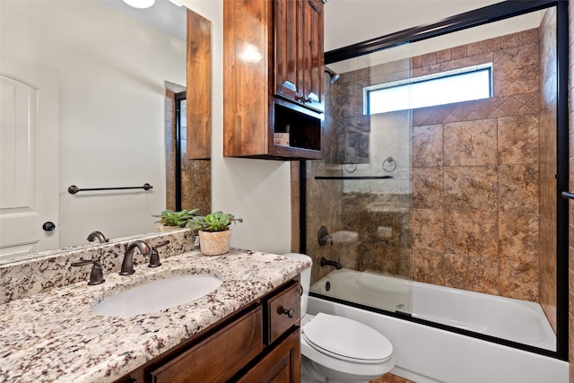 full bath featuring vanity, toilet, and combined bath / shower with glass door