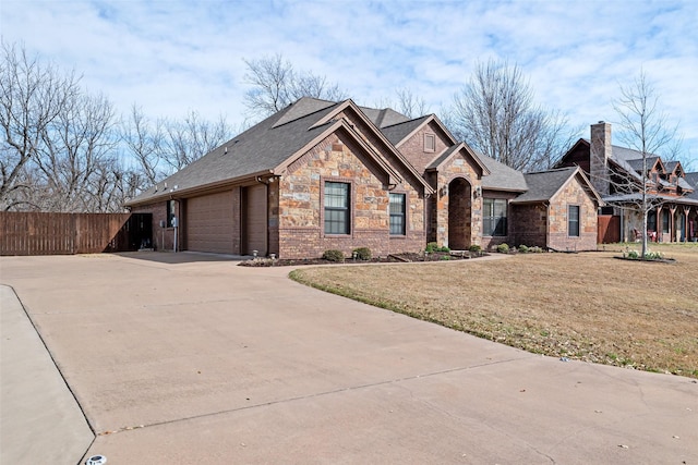 view of front of property with a front lawn, fence, a garage, stone siding, and driveway