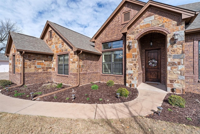 view of front of house with stone siding and a shingled roof