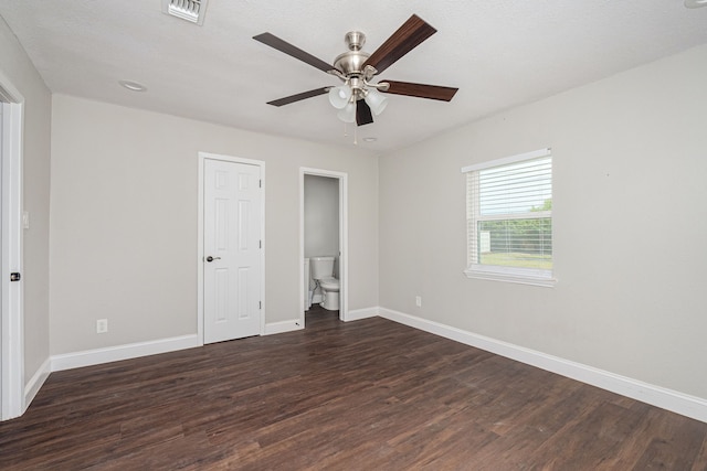 unfurnished bedroom featuring visible vents, dark wood-type flooring, ceiling fan, baseboards, and ensuite bathroom