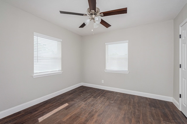 spare room with baseboards, ceiling fan, and dark wood finished floors