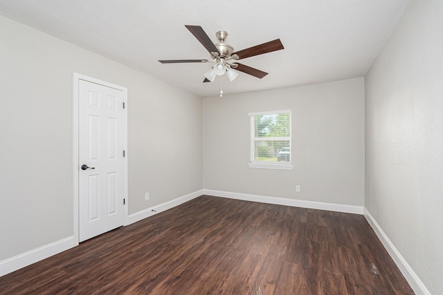 unfurnished room with baseboards, dark wood finished floors, and a ceiling fan