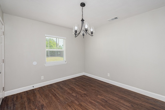 empty room featuring visible vents, baseboards, a notable chandelier, and dark wood finished floors