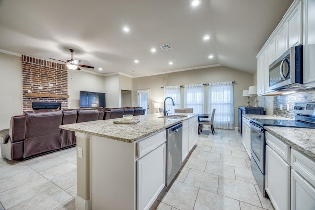 kitchen featuring a center island with sink, ceiling fan, decorative backsplash, a sink, and appliances with stainless steel finishes