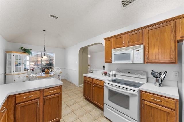 kitchen featuring visible vents, white appliances, light countertops, and lofted ceiling