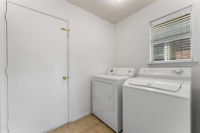 laundry area featuring light tile patterned flooring, laundry area, a textured ceiling, and separate washer and dryer