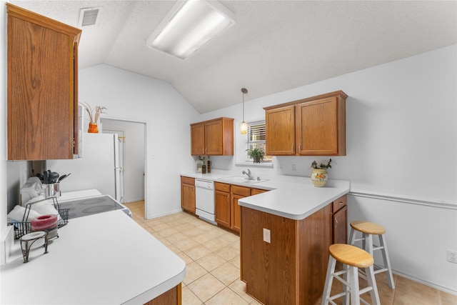 kitchen with visible vents, light countertops, brown cabinets, a peninsula, and white appliances