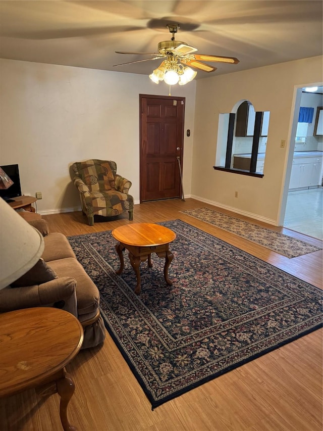 living room featuring baseboards, a ceiling fan, and wood finished floors