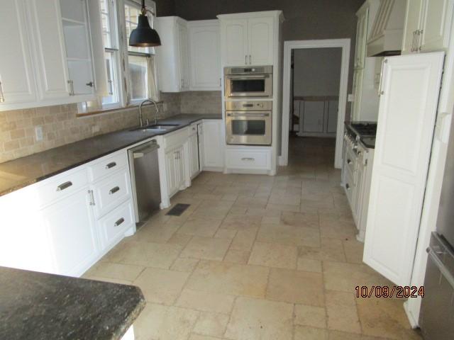 kitchen with stone tile flooring, backsplash, appliances with stainless steel finishes, and a sink