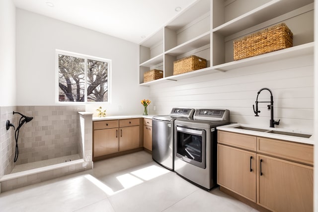 clothes washing area featuring light tile patterned flooring, cabinet space, independent washer and dryer, and a sink