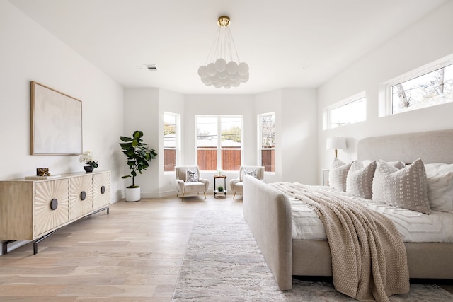 bedroom with visible vents, a notable chandelier, and wood finished floors