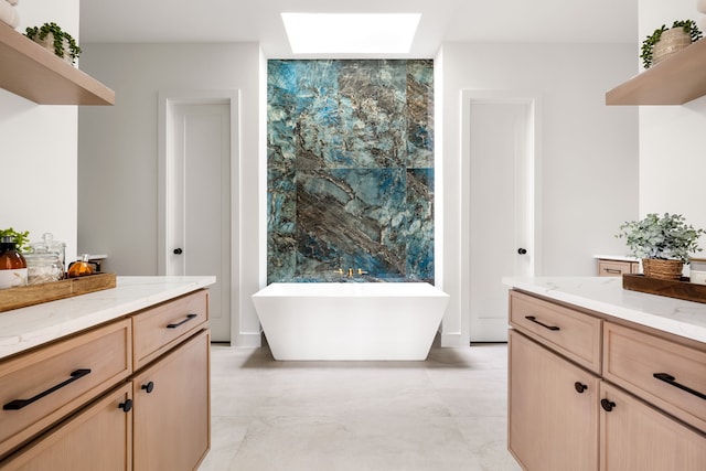 bathroom with vanity, a skylight, and a freestanding bath