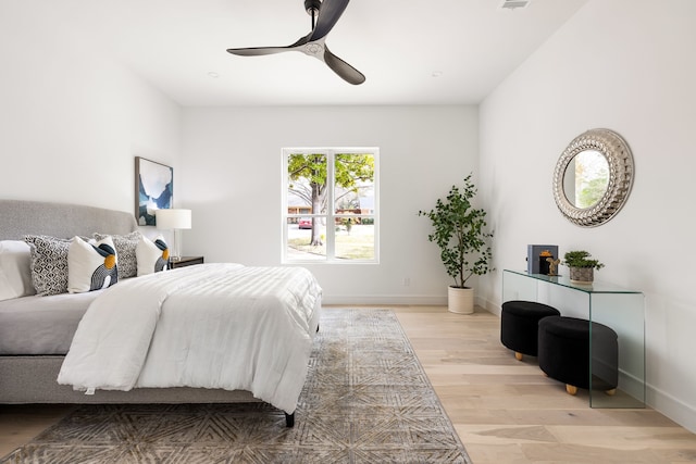 bedroom with visible vents, baseboards, a ceiling fan, and light wood finished floors