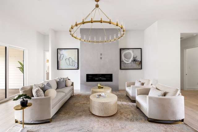 living room featuring a notable chandelier, a large fireplace, and wood finished floors