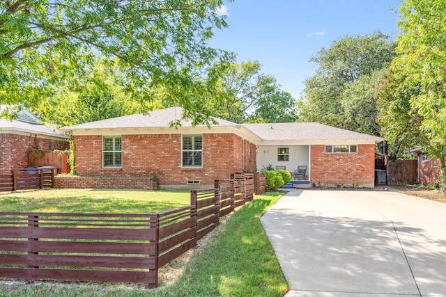 ranch-style home with a front lawn, fence, brick siding, and driveway