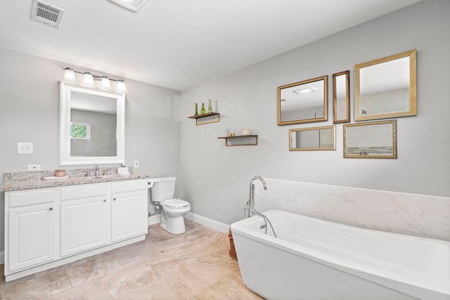 bathroom featuring visible vents, baseboards, toilet, a freestanding tub, and vanity