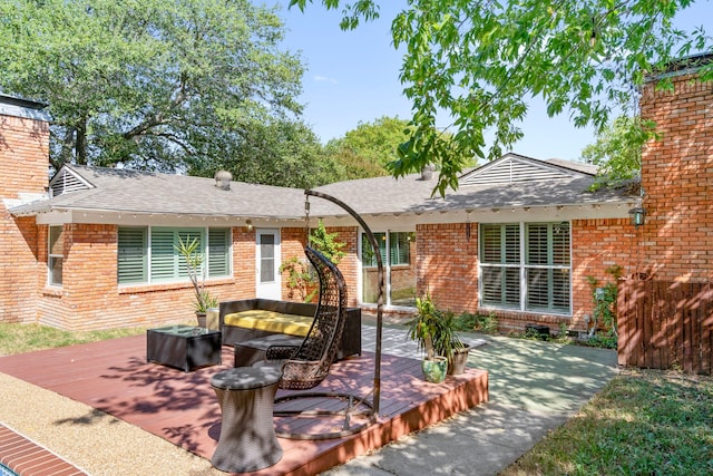 exterior space featuring a deck, brick siding, and roof with shingles