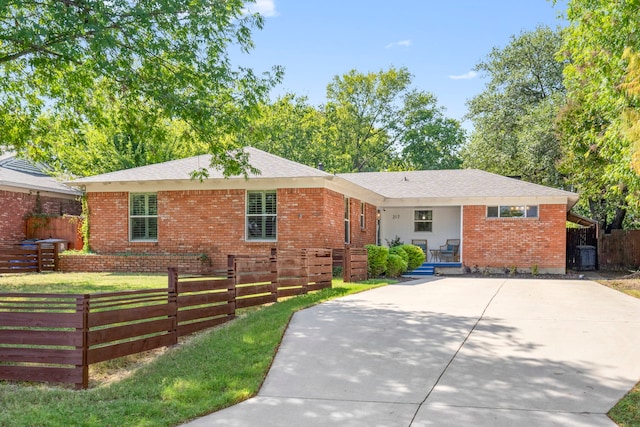 ranch-style house featuring a fenced front yard, brick siding, and driveway