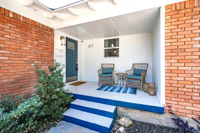 doorway to property with covered porch and brick siding