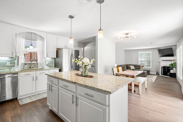 kitchen with a sink, tasteful backsplash, appliances with stainless steel finishes, white cabinets, and dark wood-style flooring