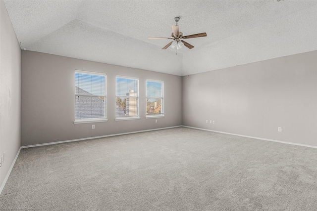 carpeted spare room with a textured ceiling, baseboards, ceiling fan, and vaulted ceiling