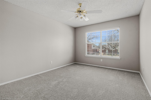 carpeted spare room featuring baseboards, a textured ceiling, and a ceiling fan