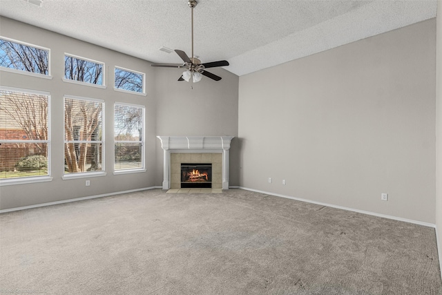 unfurnished living room with a tile fireplace, a ceiling fan, baseboards, and carpet floors