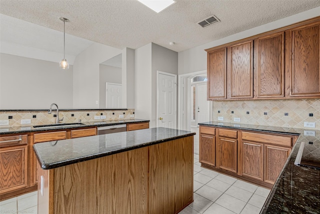 kitchen with visible vents, a sink, dark stone counters, light tile patterned floors, and dishwasher