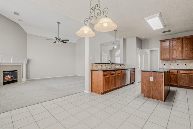 kitchen with visible vents, stainless steel dishwasher, dark countertops, light colored carpet, and open floor plan