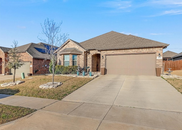 view of front of house featuring brick siding, a front yard, roof with shingles, a garage, and driveway