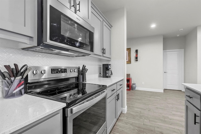 kitchen featuring baseboards, gray cabinets, light wood-style floors, appliances with stainless steel finishes, and backsplash