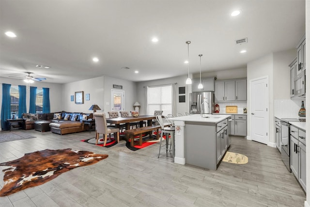 kitchen with visible vents, open floor plan, light countertops, gray cabinets, and appliances with stainless steel finishes