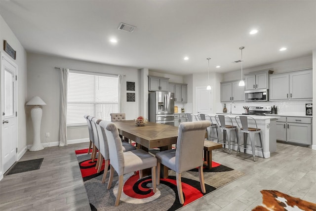 dining room featuring light wood finished floors, visible vents, recessed lighting, and baseboards