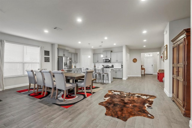 dining room with light wood finished floors, visible vents, recessed lighting, and baseboards