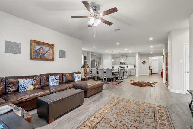 living room featuring light wood-type flooring, visible vents, recessed lighting, baseboards, and ceiling fan