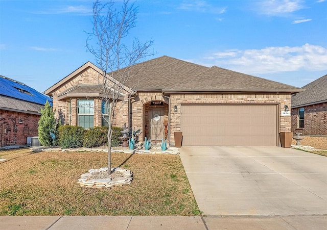 french provincial home featuring concrete driveway, a front yard, a shingled roof, a garage, and brick siding