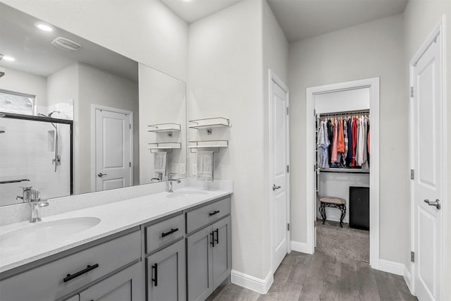 bathroom with a sink, visible vents, wood finished floors, and a stall shower