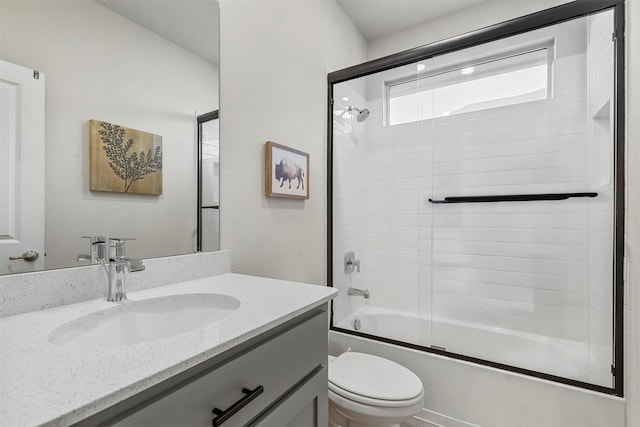 bathroom with toilet, vanity, and shower / bath combination with glass door