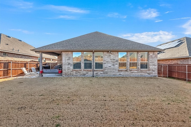 rear view of house with a patio area, brick siding, a fenced backyard, and a shingled roof