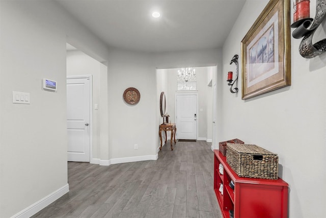 hall with recessed lighting, baseboards, an inviting chandelier, and wood finished floors