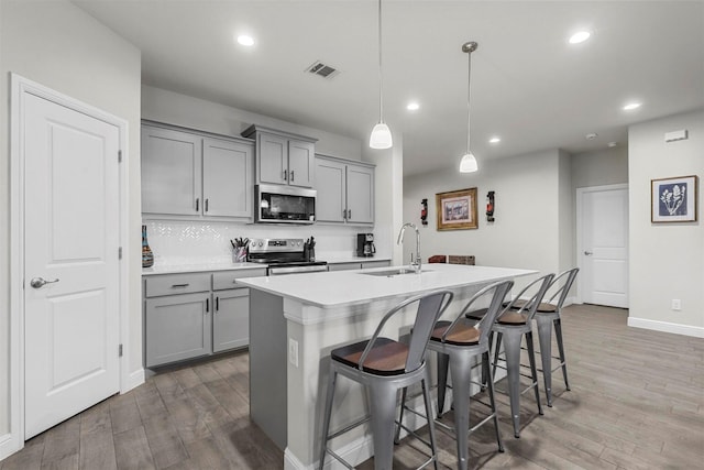 kitchen featuring visible vents, gray cabinets, stainless steel appliances, and a sink