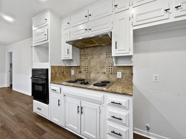 kitchen with under cabinet range hood, black oven, stainless steel electric cooktop, and dark stone counters