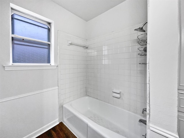 full bathroom featuring washtub / shower combination, baseboards, and wood finished floors