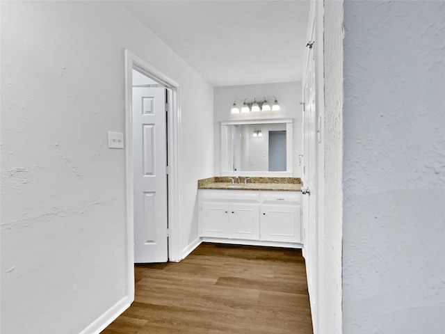 bathroom featuring vanity, wood finished floors, and baseboards