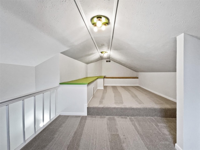 bonus room featuring baseboards, visible vents, carpet floors, lofted ceiling, and a textured ceiling