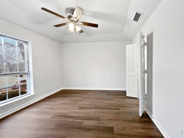 empty room featuring visible vents, baseboards, a ceiling fan, and dark wood-style flooring