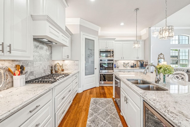 kitchen featuring light wood-style flooring, a notable chandelier, white cabinets, stainless steel appliances, and a sink