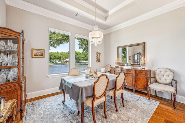 dining space with wood finished floors, baseboards, visible vents, ornamental molding, and a chandelier